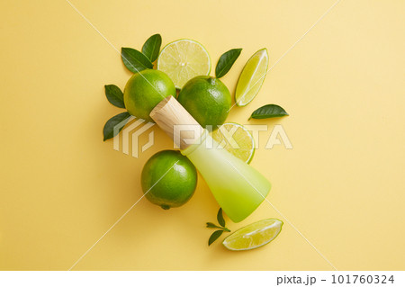 Empty label jar with wooden cap is arranged with Lime and green leaves over light background. Lime (Citrus aurantiifolia) is used to slow down the aging process 101760324