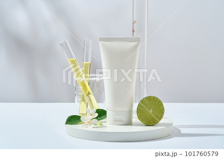 Scene for advertising cosmetic of lime extract with plastic bottle unlabeled, halves of lime and lab glassware filled yellow liquid on white background. Research and production of natural cosmetics 101760579