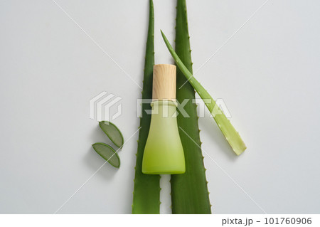Mockup scene for cosmetics from natural ingredients - green glass bottle unlabeled, aloe vera leaves and slices decorated on white background. Minimal concept for advertising product with aloe vera 101760906