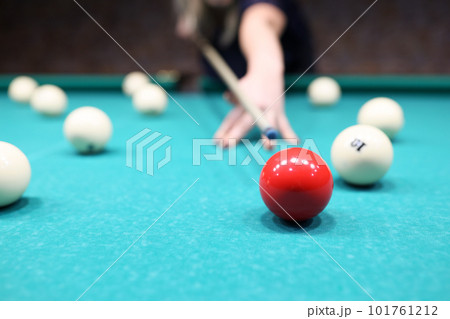 Female player ready to hit red ball on blue pool table Female player ready to hit red ball on blue pool table 101761212