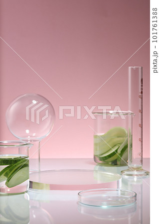 Over a purple background, a transparent podium in round shape displayed with two beakers of Cucumber and some glassware. Cucumber (Cucumis sativus) is rich in vitamin C Over a purple background, a transparent podium in round shape displayed with two beakers of Cucumber and some glassware. Cucumber (Cucumis sativus) is rich in vitamin C 101761388