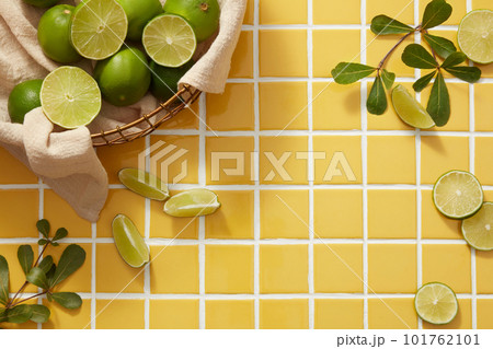 A bamboo basket of Lime arranged with tree branch and Lime slices on yellow tiles background. Vacant space to display beauty product extracted from Lime (Citrus aurantiifolia) A bamboo basket of Lime arranged with tree branch and Lime slices on yellow tiles background. Vacant space to display beauty product extracted from Lime (Citrus aurantiifolia) 101762101