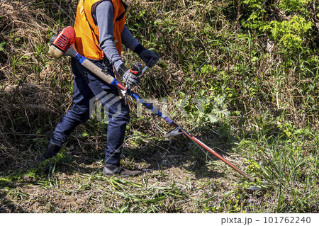生い茂った雑草を電動草刈機で刈り込む男性植木職人 生い茂った雑草を電動草刈機で刈り込む男性植木職人 101762240