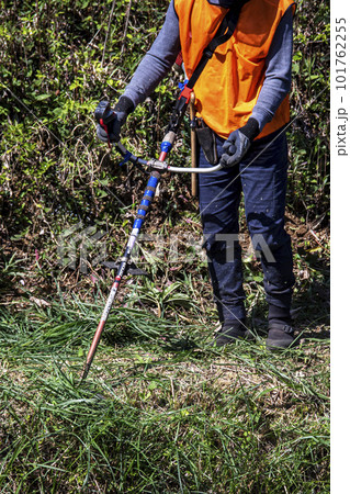 生い茂った雑草を電動草刈機で刈り込む男性植木職人 生い茂った雑草を電動草刈機で刈り込む男性植木職人 101762255
