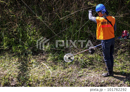 生い茂った雑草を電動草刈機で刈り込む男性植木職人 生い茂った雑草を電動草刈機で刈り込む男性植木職人 101762292