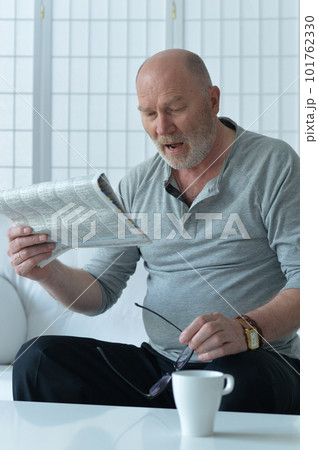 Senior old man reading newspaper at home 101762330