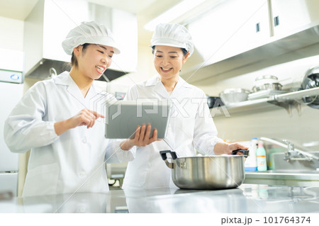 タブレットを見ながら料理する調理師の女性 101764374