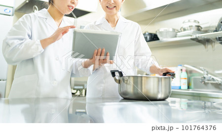 タブレットを見ながら料理する調理師の女性 101764376