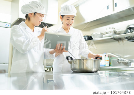 タブレットを見ながら料理する調理師の女性 タブレットを見ながら料理する調理師の女性 101764378