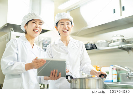 タブレットを見ながら料理する調理師の女性 タブレットを見ながら料理する調理師の女性 101764380