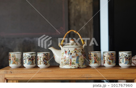 side view one ceramic kettle and six ceramic cups on glass and wood cabinet, object, decor, kitchen, copy space 101767960