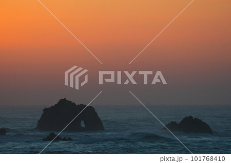 朝焼けに染まる伊良湖岬に打ち寄せる荒波と沖の石門を恋路ヶ浜より臨む 101768410