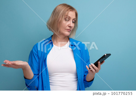 a woman of mature years makes a payment from a smartphone on a blue background copy space a woman of mature years makes a payment from a smartphone on a blue background copy space 101770255