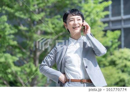 新緑の屋外でスマホで会話するキャリアウーマン 新緑の屋外でスマホで会話するキャリアウーマン 101770774