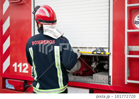 Firefighter in uniform and protective helmet, opening storage cabinet, getting ready for action 101772720