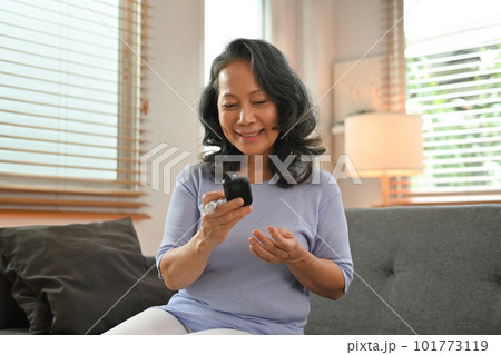 Happy senior woman checking blood sugar level by digital glucose meter. Healthcare and medical, diabetes concept Happy senior woman checking blood sugar level by digital glucose meter. Healthcare and medical, diabetes concept 101773119