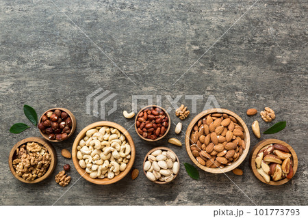 mixed nuts in wooden bowl. Mix of various nuts on colored background. pistachios, cashews, walnuts, hazelnuts, peanuts and brazil nuts 101773793