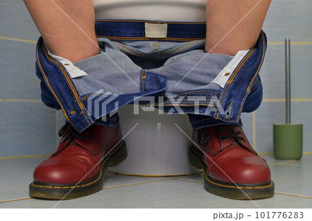 A man sitting on the toilet. A concept from the 1980s. Red punk shoes and jeans. Gender theme and urban culture. A man sitting on the toilet. A concept from the 1980s. Red punk shoes and jeans. Gender theme and urban culture. 101776283