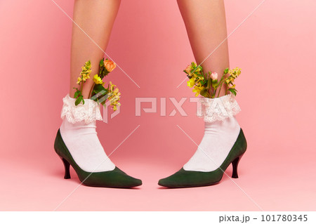 Close up portrait of female feet wearing shoose and white fancy socks with flower inside over pink studio background. Spring fashion Close up portrait of female feet wearing shoose and white fancy socks with flower inside over pink studio background. Spring fashion 101780345