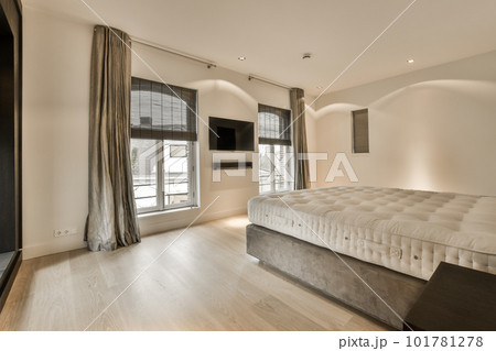 a bedroom with white walls and hardwood flooring, including a large bed in the room has a flat screen tv on the wall a bedroom with white walls and hardwood flooring, including a large bed in the room has a flat screen tv on the wall 101781278