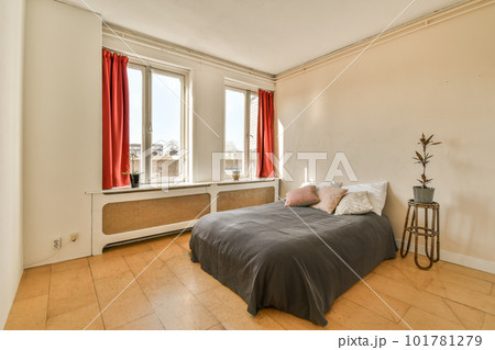 a bed in a room with red drapes on the window is open and there is a plant next to it a bed in a room with red drapes on the window is open and there is a plant next to it 101781279