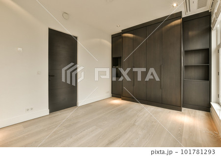 an empty room with wood flooring and black wardrobes on either side by the wall, there is no one in it 101781293