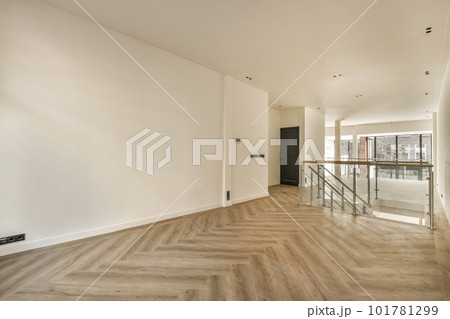 an empty living room with wood flooring and white walls on either side of the room there is a staircase leading up to the an empty living room with wood flooring and white walls on either side of the room there is a staircase leading up to the 101781299