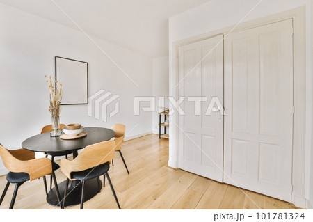 a dining room with white walls and wood flooring the table is surrounded by four chairs in front of the door 101781324