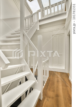 a white house with wood floors and stairs leading up to the second floor in an open living room on a sunny day a white house with wood floors and stairs leading up to the second floor in an open living room on a sunny day 101781331