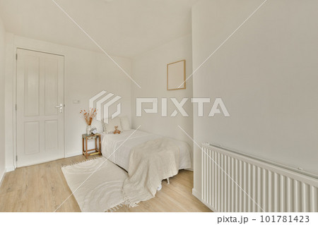a bedroom with white walls and wood flooring in the room, there is a small bed on the right side 101781423