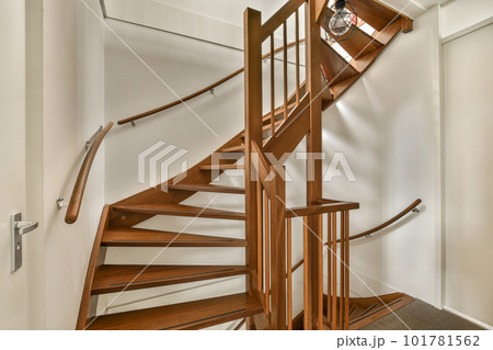 a wooden spiral staircase in a white room with hardwood flooring and wood handrails on the wall behind a wooden spiral staircase in a white room with hardwood flooring and wood handrails on the wall behind 101781562