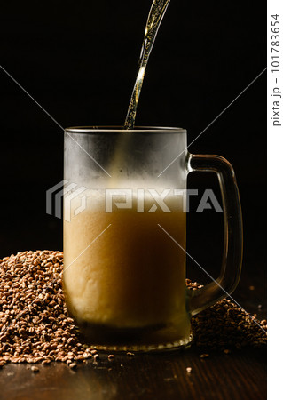 Beer is poured into a cold beer glass on a dark background. 101783654