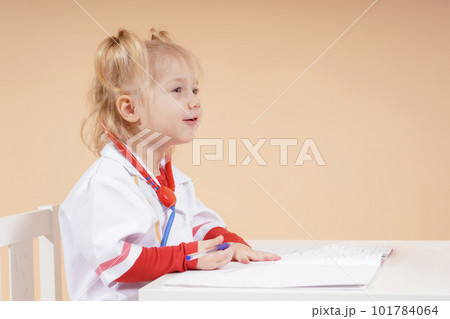 The child, as a doctor with a toy stethoscope, listens to the patient at the reception and keeps a patient's medical history. The child, as a doctor with a toy stethoscope, listens to the patient at the reception and keeps a patient's medical history. 101784064