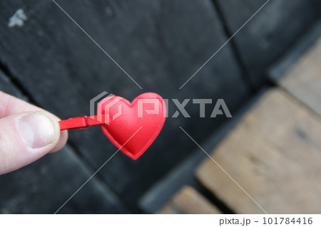 A hand holds a red heart on a vintage background. 101784416