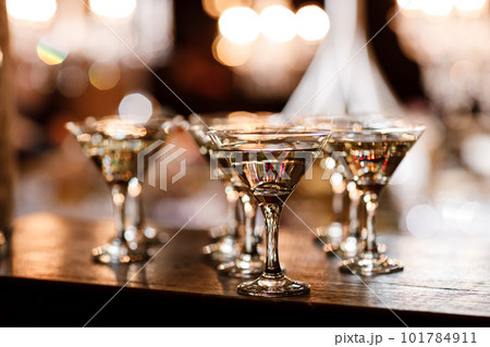martini glasses in front of gold bokeh background. Luxury cocktail drink in restaurant bar with night lights blur. Classy beverage celebration party for new year, christmas, valentine. 101784911