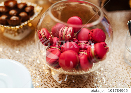 Colorful macarons stand in round transparent weight as part of candy bar sweet table. French macaroons. Candy bar. 101784966