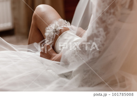The bride holds in hand lose-up garter in hotel room. morning preparation wedding concept. The bride holds in hand lose-up garter in hotel room. morning preparation wedding concept. 101785008