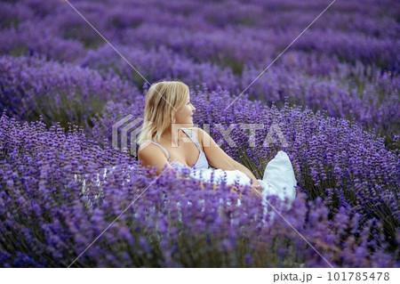 A middle-aged woman sits in a lavender field and enjoys aromatherapy. Aromatherapy concept, lavender oil, photo session in lavender 101785478