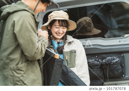 秋冬のアウトドア・キャンプ場にキャンプに来て車の荷台から荷物を運ぶ仲間達（男女・アジア人） 101787078