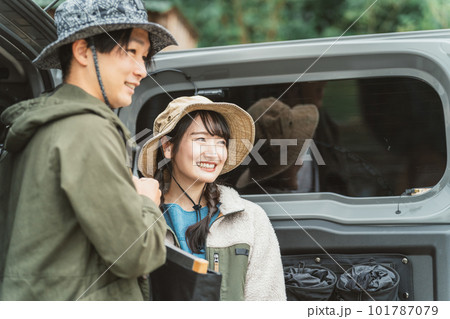 秋冬のアウトドア・キャンプ場にキャンプに来て車の荷台から荷物を運ぶ仲間達（男女・アジア人） 101787079