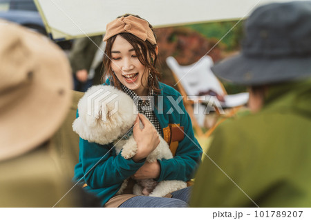 秋冬のキャンプ場で愛犬を抱くキャンパーのアジア人女性（ビジョンフリーゼ） 101789207
