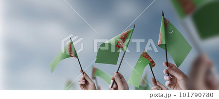 A group of people holding small flags of the Turkmenistan in their hands A group of people holding small flags of the Turkmenistan in their hands 101790780