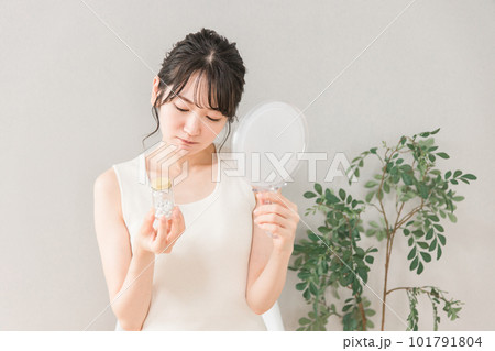 ビタミン剤・サプリメントが効かない肌荒れ・ニキビに悩む鏡を持つアジア人女性 101791804
