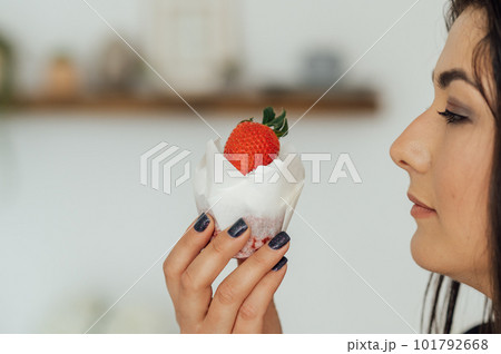 Close up portrait of pretty young brunette woman with bright make up eating tasty cake with berries and cream 101792668