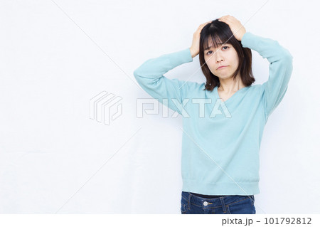 白い背景の前で頭を抱えて悩む30代の女性 白い背景の前で頭を抱えて悩む30代の女性 101792812