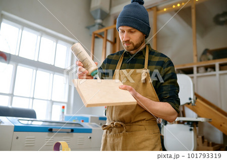 Portrait of experienced man carpentry worker applying glue on board 101793319