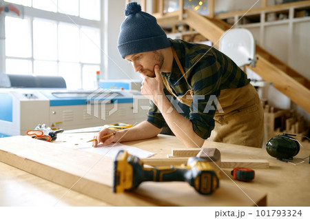 Pensive carpenter designer looking at plan scheme on work table Pensive carpenter designer looking at plan scheme on work table 101793324