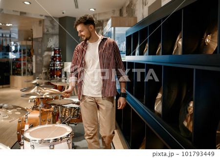 Young man buyer choosing drums at modern music shop 101793449