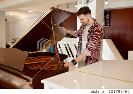 Man buyer looking on tuning keys inside grand piano under lid 101793460