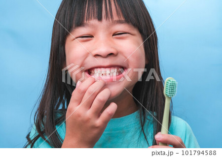 Smiling cute little girl holding toothbrush isolated on blue background. Cute little child brushing teeth. Kid training oral hygiene, Tooth decay prevention or dental care concept. Smiling cute little girl holding toothbrush isolated on blue background. Cute little child brushing teeth. Kid training oral hygiene, Tooth decay prevention or dental care concept. 101794588